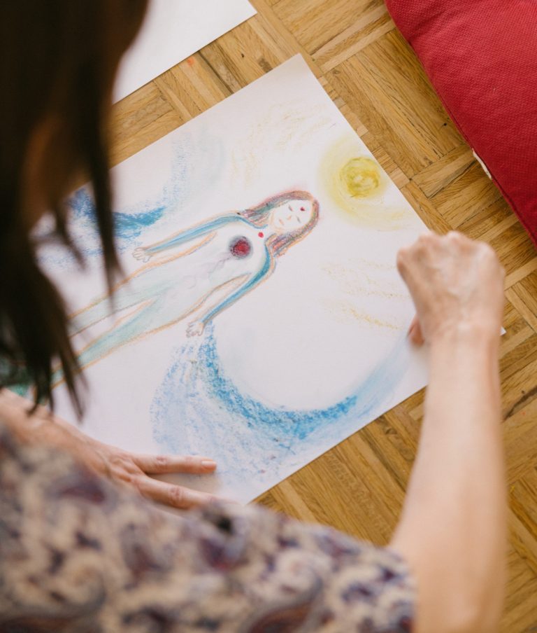 Mujer dibujando una figura femenina durante una sesión de arteterapia