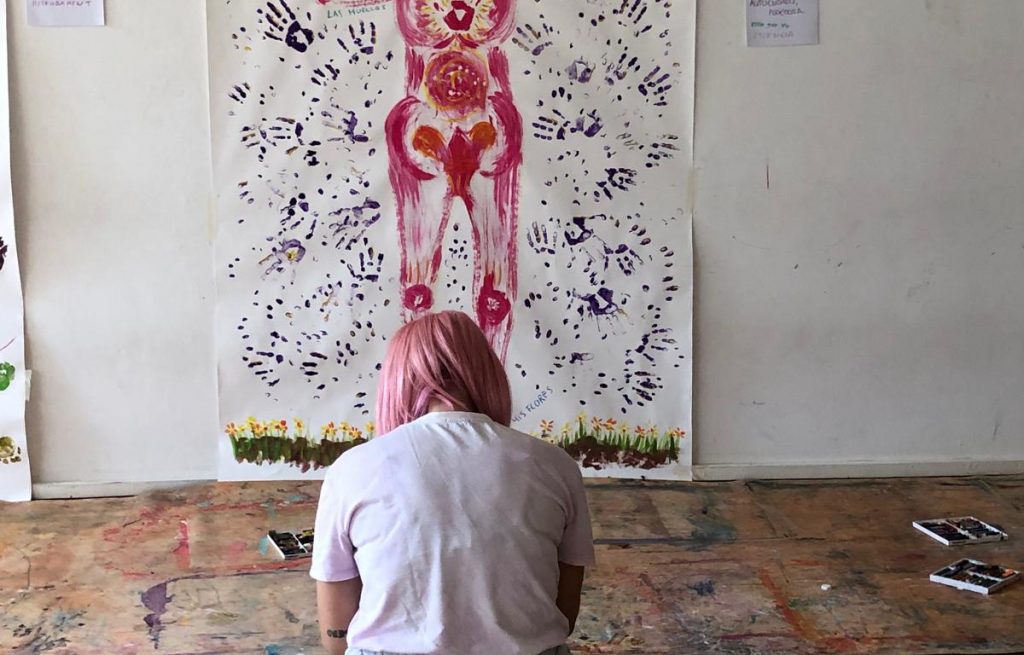 Cartografía corporal en pintura colgada de la pared con alumna de arteterapia tomando apuntes durante un Introductorio de Arteterapia Gestalt