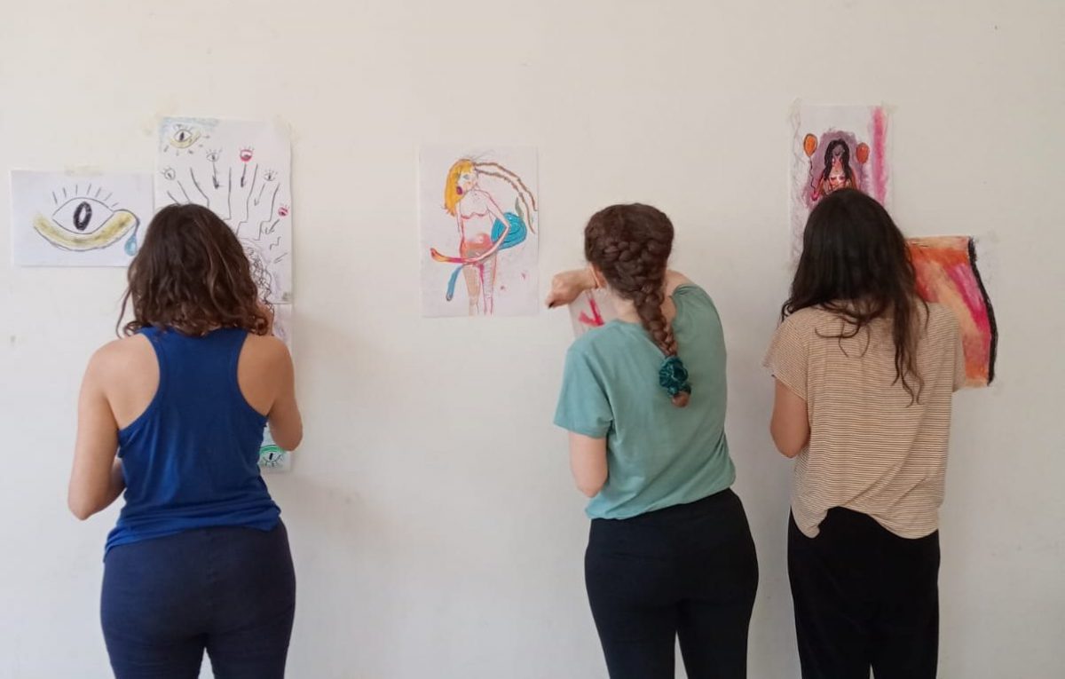 Tres mujeres haciendo trabajos de arteterapia gestalt sobre la pared.